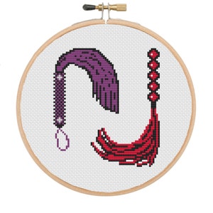 May include: A cross-stitch embroidery hoop with two whips, one purple and one red, with beads on the red whip.