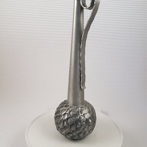 K&ouml;nnte beinhalten: Eine silberne Metallvase mit einem strukturierten, runden Boden und einem langen, schlanken Hals. Die Vase hat einen einzigartigen, gekr&auml;uselten Griff.