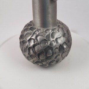 K&ouml;nnte beinhalten: Ein silberner Metall-Gardinenknauf mit einem strukturierten, runden Kugeldesign. Der Knauf ist f&uuml;r die Verwendung mit Vorh&auml;ngen oder Gardinen gedacht.