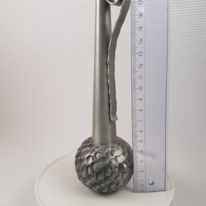 K&ouml;nnte beinhalten: Eine silberne Metallvase mit einem strukturierten, runden Boden und einem hohen, schlanken Hals. Die Vase hat einen dekorativen, gekr&auml;uselten Griff.