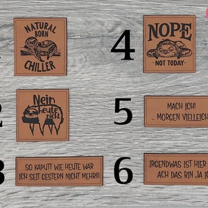 Könnte beinhalten: Sechs braune Leder-Patches mit Faultier-Illustrationen und humorvollen Sprüchen. Die Patches beinhalten "Natural Born Chiller", "Nope - Not Today", "Nein Heute Nicht", "Mach Ich! Morgen Vielleicht", "So Kaputt Wie Heute War Ich Seit Gestern Nicht Mehr!!!" und "Irgendwas Ist Hier Fauli Ach Das Bin Ja Ich!"