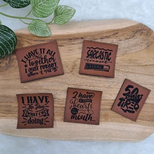 Könnte beinhalten: Eine weiße Keramik-Tasse mit schwarzem Henkel und dem Text "But First, Coffee" in schwarzer, fetter Schrift. Die Tasse steht auf einer Holzoberfläche.