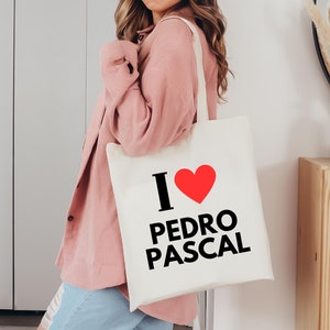 May include: A white tote bag with a black graphic that says "I love Pedro Pascal" with a red heart.