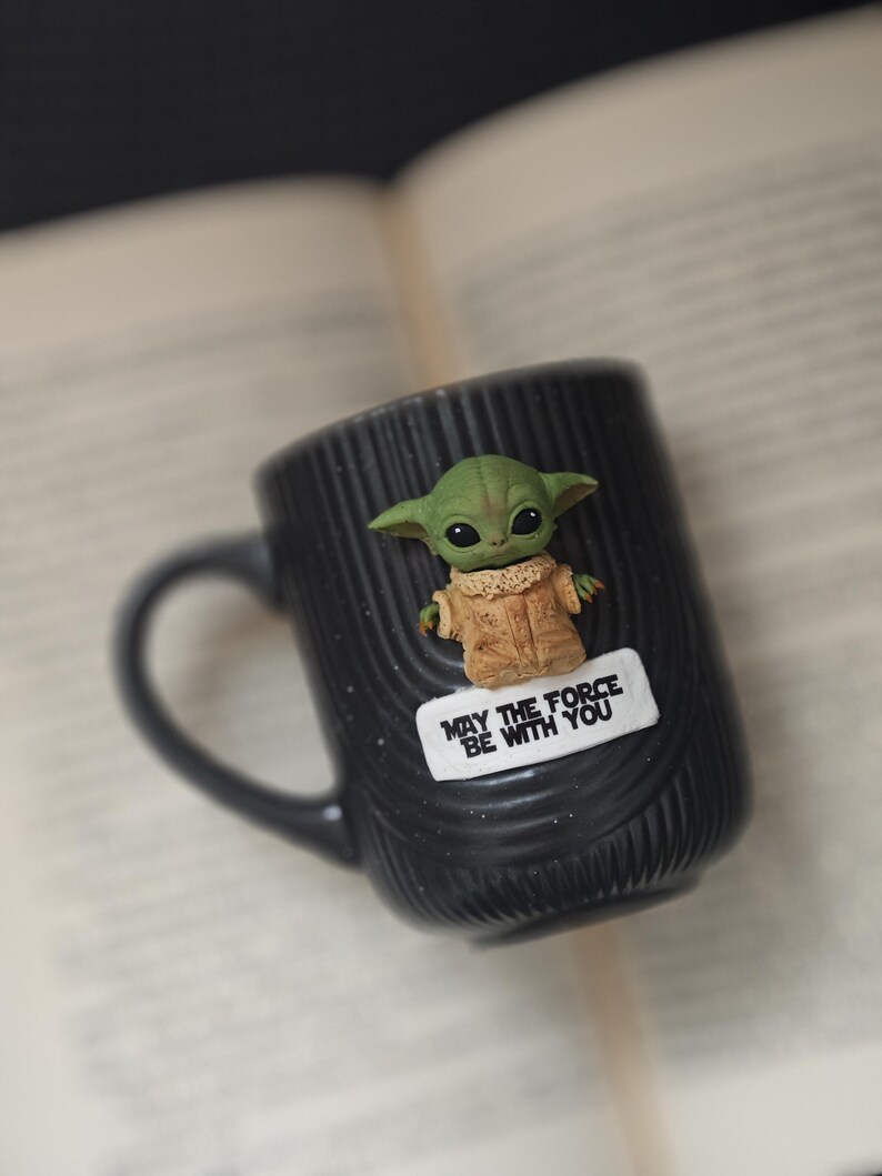 Pu&ograve; includere: Una tazza di ceramica bianca con manico nero e la scritta "But First, Coffee" in grassetto nero. La tazza &egrave; appoggiata su una superficie di legno. La tazza &egrave; alta circa 10 cm.