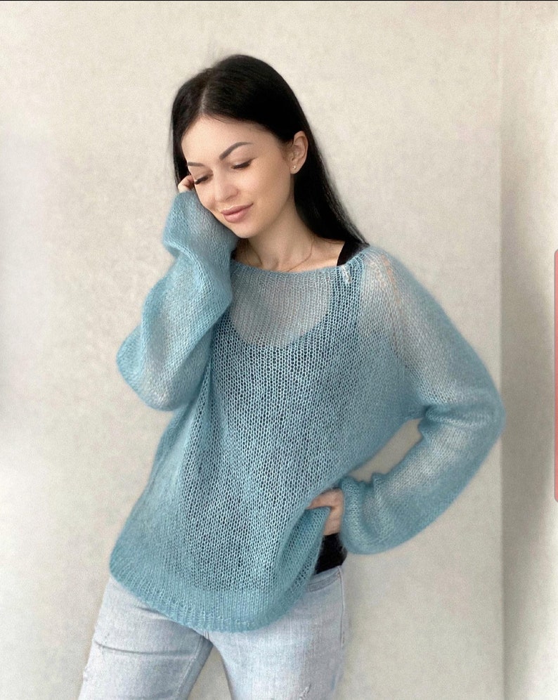 May include: A light blue, sheer knit sweater with a loose fit and long sleeves.