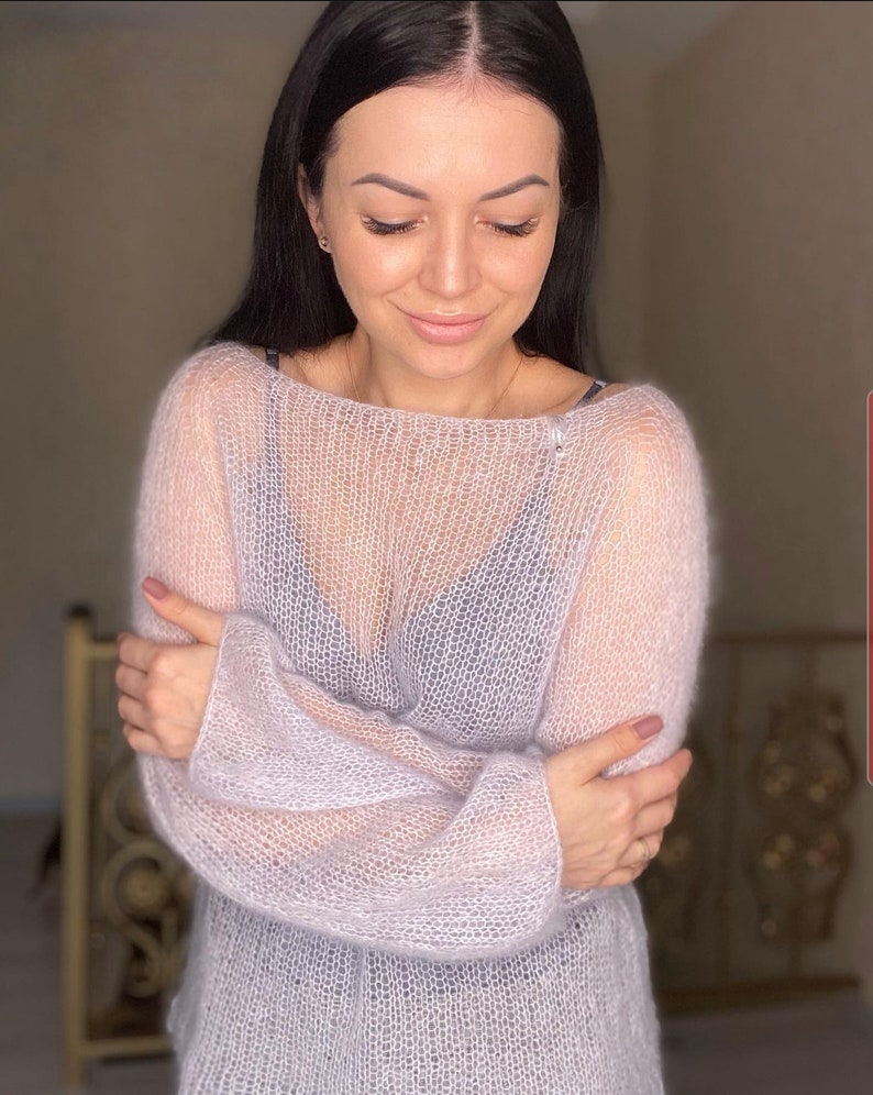 May include: A light purple, sheer, knitted sweater with long sleeves.