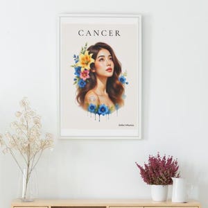 Peut inclure: Une affiche encadrée avec une illustration à l'aquarelle d'une femme ornée de fleurs. Le mot "CANCER" est imprimé en haut. La femme a de longs cheveux bruns et est entourée de fleurs bleues, jaunes et roses.