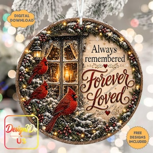 Peut inclure: Une décoration de Noël ronde illustrant trois cardinaux rouges perchés sur des branches de pin enneigées près d'une fenêtre. Le texte indique Always remembered Forever Loved. Le motif inclut des lumières, des pommes de pin et des baies rouges.