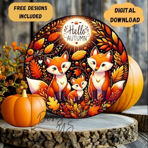 May include: A round, colorful illustration of three foxes in a forest setting. The foxes are orange and white with black eyes and noses. The background is a dark forest with leaves in shades of orange, yellow, and red. The text "Hello Autumn" is written in a white circle with a yellow star.