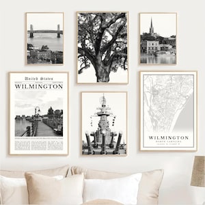 May include: A collection of six framed black and white prints. The prints depict various scenes, including a bridge, a large tree, a church, a waterfront scene with text, a battleship, and a map of Wilmington, North Carolina. The prints are displayed on a white wall.