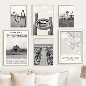 May include: A collection of framed black and white prints featuring Huntington Beach, California. The prints include images of surfboards, a pier, a street lined with palm trees, a map, and a sign that reads "Huntington Beach Surf City USA."