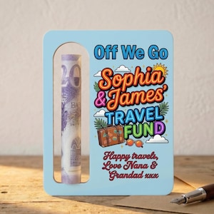 May include: A light blue travel fund money holder with a rectangular window displaying a rolled-up bill. The holder features colorful text that reads "Off We Go Sophia & James TRAVEL FUND" with a suitcase and sunglasses graphic. The text "Happy travels, Love Nana & Grandad xxx" is also included.