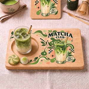 May include: A rectangular wooden serving board featuring a circular indentation for a glass of iced matcha latte with a bamboo straw. The board displays a green and peach graphic with the text "MATCHA CLUB" and "Sip Slow" alongside leaf motifs.