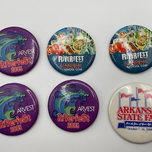 May include: Six round buttons with various designs.  Three purple buttons with a blue and green wave design and the text "ARVEST RiVerfeSt 2005". One blue button with a colorful design and the text "RIVERFEST LANDERS TOYOTA.COM". One white button with a colorful design and the text "RIVERFEST LANDERS JOYOTA.COM". One white button with red and blue flags and the text "ARKANSAS STATE FAIR For the Time of Your Life! October 7-16, 1988".
