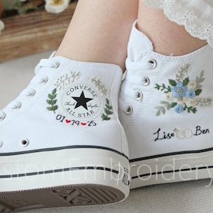 Puede incluir: Zapatillas Converse blancas de caña alta con diseños florales bordados y detalles personalizados. Un zapato tiene el texto "01♥19♥25" y el otro tiene el texto "Lise & Ben".