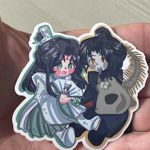 May include: Two anime-style characters, one with long black hair and a white and green outfit holding a fan, the other with black hair and a brown outfit, are depicted in a sticker.