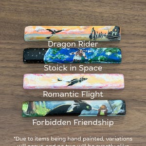 Może przedstawiać: Cztery prostokątne, ręcznie malowane przedmioty drewniane z grafiką o tematyce smoków. Przedmioty są oznaczone jako "Dragon Rider", "Stoick in Space", "Romantic Flight" i "Forbidden Friendship". Przedmioty znajdują się na drewnianej powierzchni. Tekst na dole mówi: "Ze względu na ręczne malowanie przedmiotów, wystąpią różnice i żadne dwa nie będą identyczne."