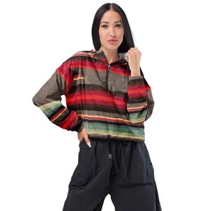May include: A cropped, striped hooded jacket with a zipper closure. The jacket has a colorful striped pattern in shades of red, brown, green, and white. The jacket is made of a lightweight fabric and has a drawstring at the waist.
