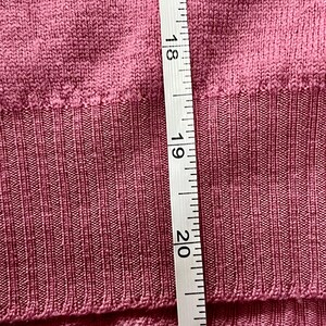 May include: A mauve-colored knit sweater featuring a ribbed hemline. A white measuring tape is placed vertically against the fabric, showing a length measurement extending from approximately 17 inches to 21 inches along the ribbed section.