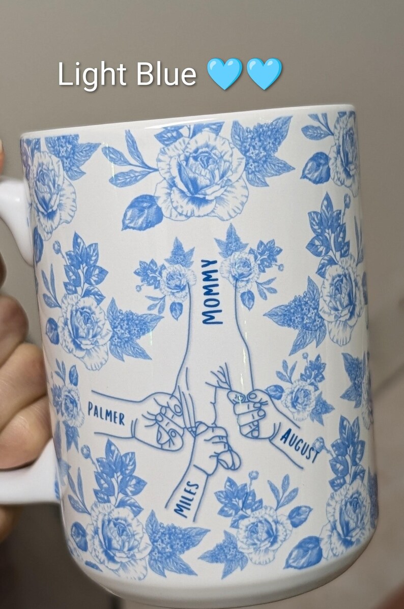 May include: White ceramic mug with a light blue floral pattern and the words "Light Blue" and two blue hearts at the top. The mug features a family-themed design with the words "Mommy", "Palmer", "Miles", and "August" in a blue script.