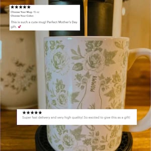 May include: White ceramic mug with a floral pattern in shades of green. The mug has the word "MOMMY" printed on it. The mug is 15 oz.