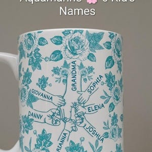 May include: White ceramic mug with a teal floral pattern and the words "Aquamarine 6 Kid's Names." The mug features six names: Giovanna, Danny, Arianna, Joshua, Elena, and Sophia. The mug has a white handle.