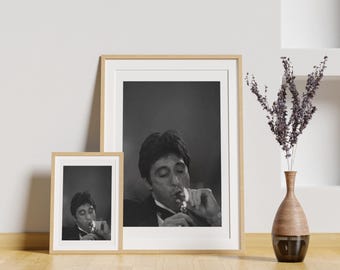Op de afbeelding: Twee ingelijste zwart-witfoto's van een man die een sigaar rookt. De grotere lijst is rechts en de kleinere lijst is links. De man in de grotere lijst kijkt naar de camera en de man in de kleinere lijst kijkt naar de zijkant. Beide lijsten hebben een lichte houtkleur.