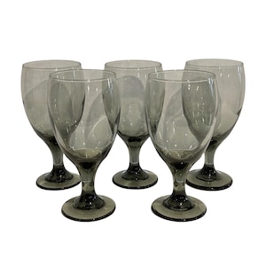 Op de afbeelding: Set van vijf grijs getinte wijnglazen. Elk glas heeft een afgeronde kom, een slanke steel en een cirkelvormige voet. De glazen zijn in een groep gerangschikt, waarbij hun ontwerp en kleur tegen een witte achtergrond worden benadrukt. Ideaal voor het serveren van wijn.