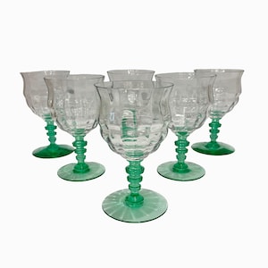 May include: A set of six clear glass goblets with a textured, wavy bowl design. Each goblet features a vibrant green stem with a multi-tiered, stacked ring detail and a matching green circular base, creating a cohesive and uniform glassware collection.
