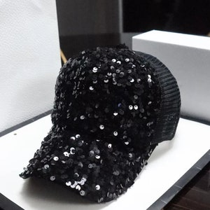 May include: A black sequined baseball cap with a mesh back.