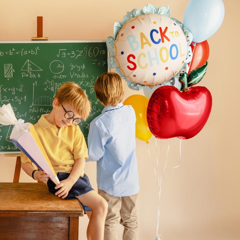 Students celebrating back to school with red apple foil balloon decoration