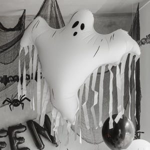 Close up of large white ghost balloon with flowing tassels in a spooky Halloween display