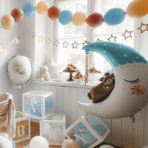 May include: A baby shower decoration with a blue and white moon balloon, a white balloon with the text "Oh Baby", and a table with a cake and other treats. There are also blue and brown balloons in the background.