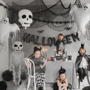 Halloween party scene with white ghost balloon, skeleton decorations and black and white party decor