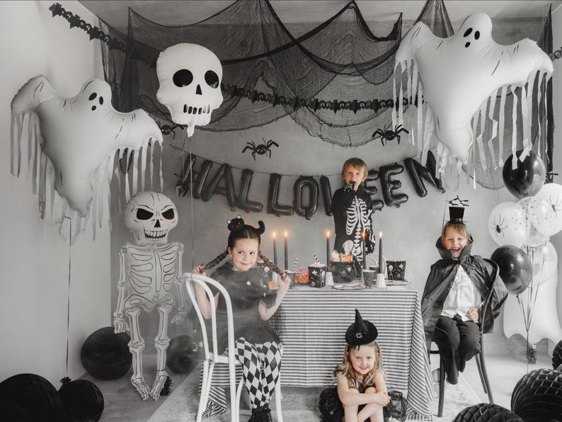 Halloween party scene with white ghost balloon, skeleton decorations and black and white party decor