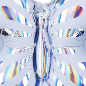 May include: A light blue iridescent foil butterfly balloon. The balloon has a holographic finish and is shaped like a butterfly with wings and a body.