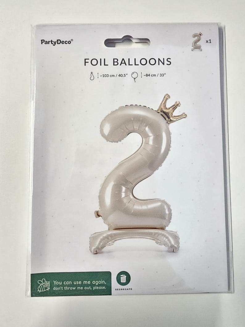 Peut inclure: Un ballon en feuille d'aluminium blanc en forme de chiffre 2 avec une couronne dor&eacute;e sur le dessus. Le ballon mesure 103 cm de haut et 84 cm de large. Le ballon est sur un fond blanc avec le texte "FOIL BALLOONS" et "PartyDeco" imprim&eacute; sur le fond.