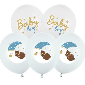 Puede incluir: Conjunto de seis globos blancos con detalles azules y dorados. Tres globos tienen el texto "Baby boy" en letras doradas. Tres globos tienen una luna creciente azul con estrellas y un oso marr&oacute;n durmiendo sobre ella.