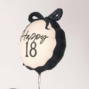 May include: Black and white balloon with a bow on top. The balloon has the text "Happy 18" printed on it.