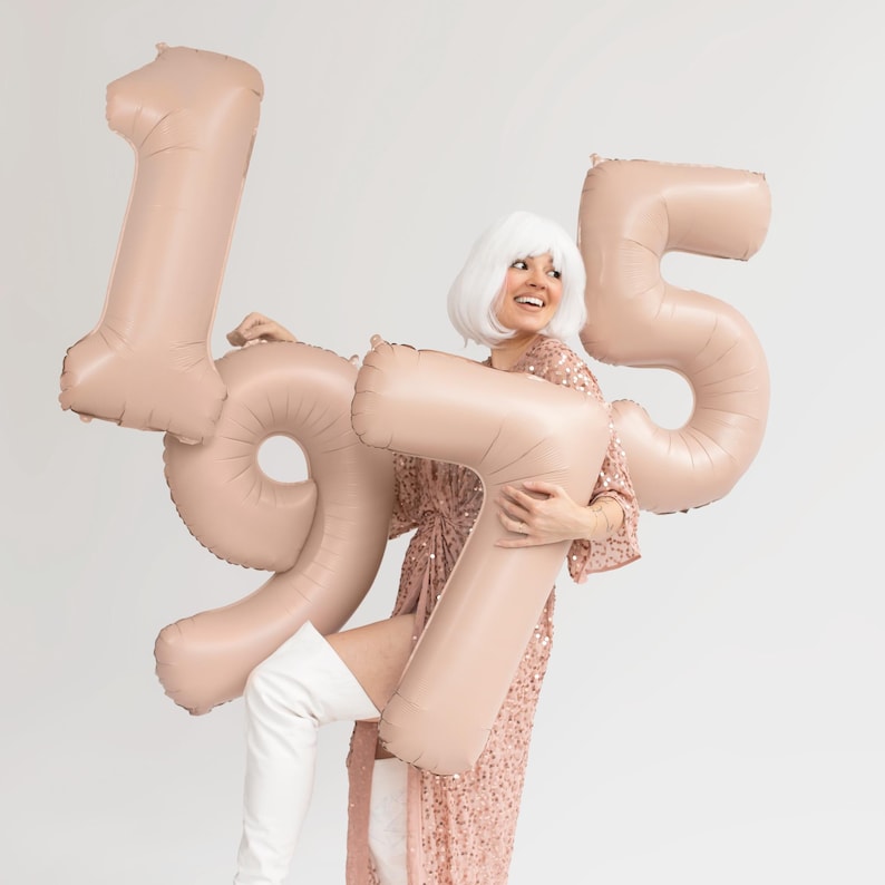 Large beige number balloons held for a birthday celebration, neutral milestone party decor with numbers 1 and 5