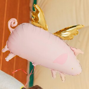 Pink flying pig foil balloon with metallic gold wings, whimsical birthday party and animal themed decoration