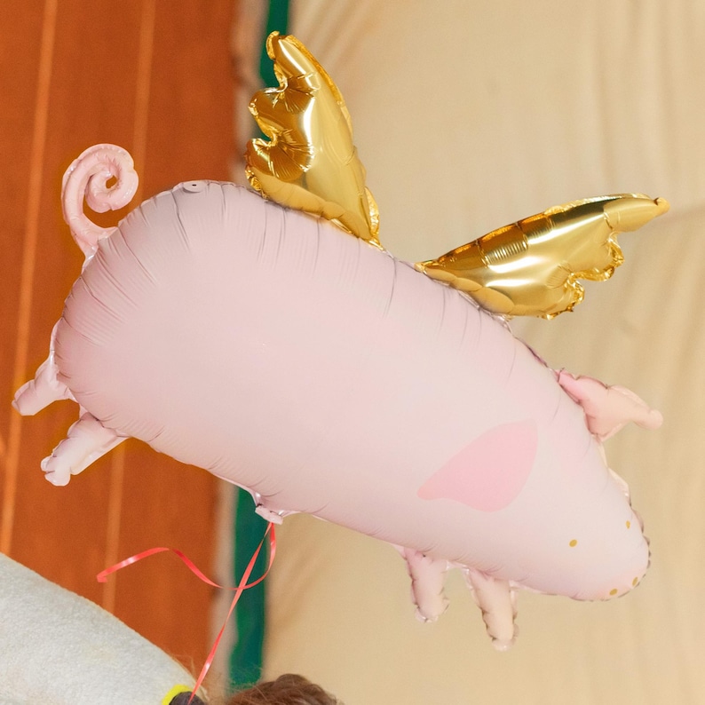 Pink flying pig foil balloon with metallic gold wings, whimsical birthday party and animal themed decoration