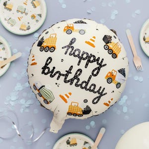 Peut inclure: Un ballon blanc sur le thème de la construction. Il présente un contour noir des mots "joyeux anniversaire" et des images de camions de chantier et de cônes.
