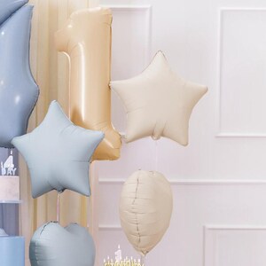 Puede incluir: Un conjunto de globos de aluminio dorados y azules para una fiesta de primer cumplea&ntilde;os. Los globos incluyen un gran n&uacute;mero uno, una estrella y un coraz&oacute;n.