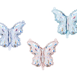May include: Three iridescent butterfly shaped foil balloons. One balloon is light blue, one is pink, and one is a darker blue.