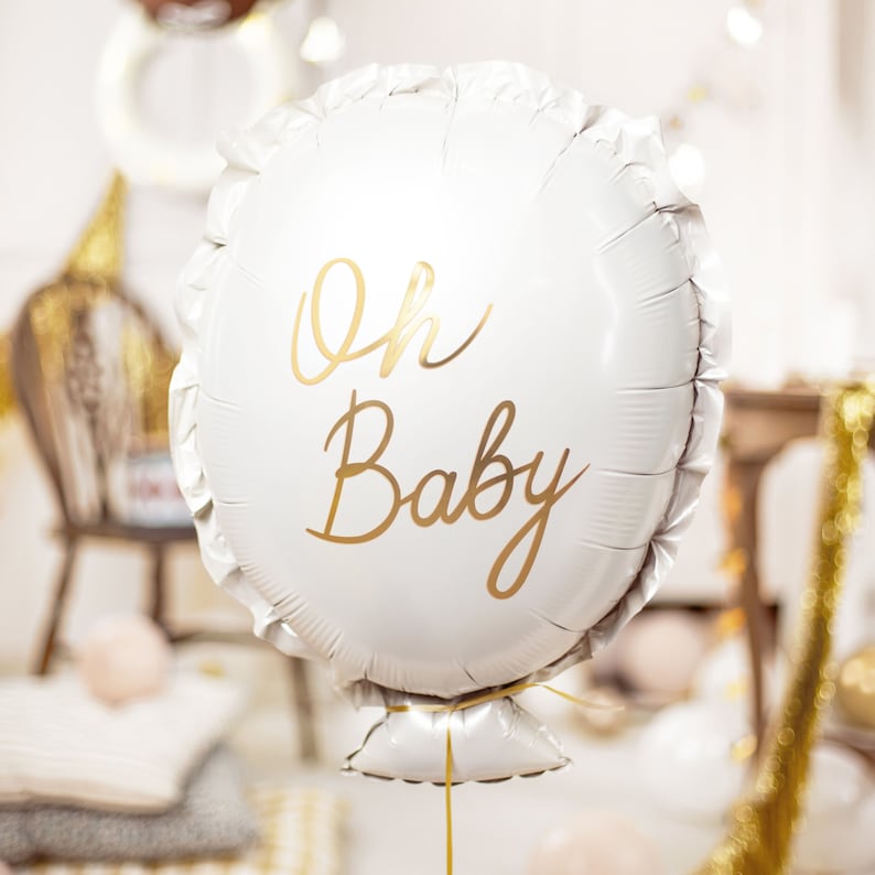 White 'Oh Baby' foil balloon with gold lettering used as baby shower decoration – elegant and festive helium balloon for gender reveal or new baby celebration.