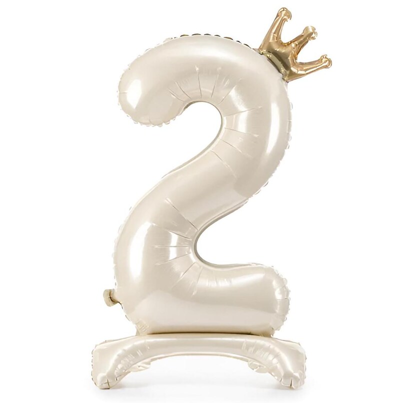 Peut inclure: Un ballon en forme de chiffre deux blanc avec une couronne dor&eacute;e sur le dessus. Le ballon est pos&eacute; sur une base blanche.