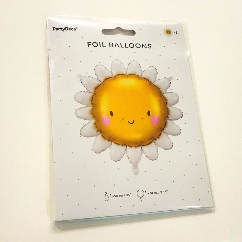 K&ouml;nnte beinhalten: Ein gelber Folienballon in Form einer l&auml;chelnden Sonne mit einer wei&szlig;en Margerite drumherum. Der Ballon hat einen Durchmesser von 90 cm. Die Verpackung tr&auml;gt die Aufschrift "Folienballons" und "PartyDeco".