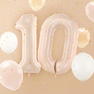 Large beige number balloons forming number 10, neutral birthday party decoration with white and gold balloons