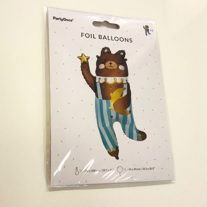 A brown bear foil balloon holding a gold star and a gold crescent moon. The balloon is wearing blue and white striped pyjamas. The balloon is 72 cm by 104 cm.